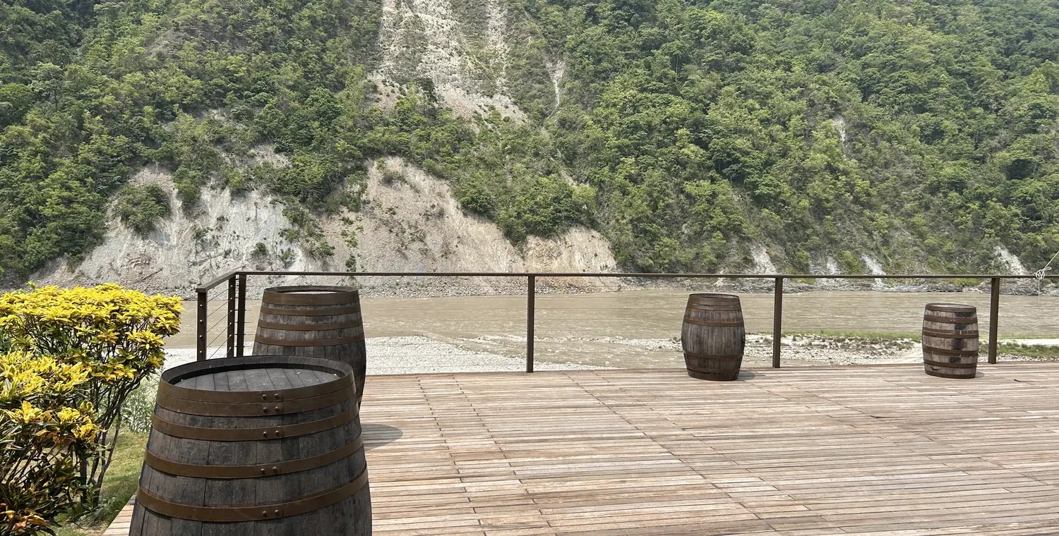 A wide open deck with a cable railing looking out over a river and a wooded slope.